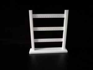 Detailed view of white 3-tier acrylic earring stand with stable base on black background