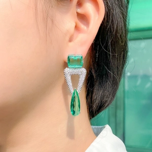 Elegant geometric S925 silver earrings with green stones on a model close-up view