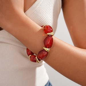 Detail of red acrylic beaded armlet with gold U-shaped clasps on female upper arm