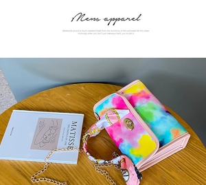 Close-up of the colorful tie-dye handbag with a golden twist lock and silk scarf handle