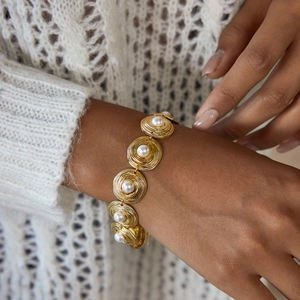 Detail of 18K gold-plated stainless steel bracelet with glossy pearls on a wrist