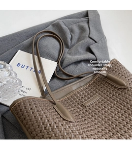 Detail shot of the woven leather texture and slender shoulder straps of the brown tote bag