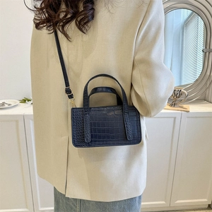Chic dark blue crocodile pattern square handbag shown on shoulder for fashion styling