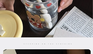 Close-up of heat-resistant glass tea cup with cartoon bear motif and a stirring spoon