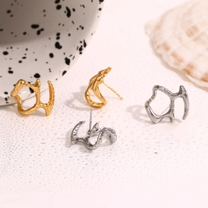 Vue détaillée de boucles d'oreilles masques abstraits en métal liquide doré et argenté