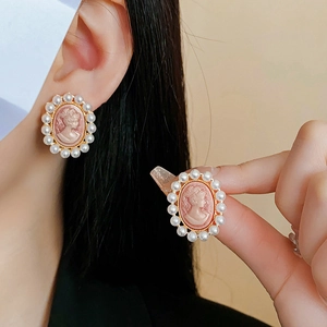 Gros plan détaillé de boucles d'oreilles vintage avec camée, perles et métal doré