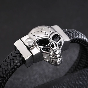 Macro shot of silver stainless steel skull clasp on black braided leather punk bracelet