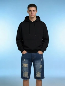 Detailed view of men's blue distressed denim shorts with fashionable ripped design