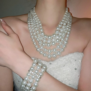 Detailed view of layered white pearl necklace and bracelet set on a female model