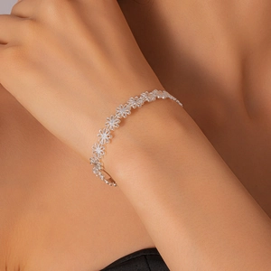 Detailed macro of a silver open cuff featuring delicate cutout floral daisy patterns