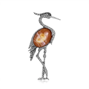 Detailed view of silver heron brooch featuring a large amber-colored textured stone