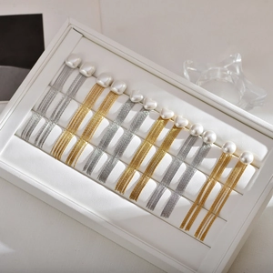 Elegant long pearl tassel earrings in gold and silver finish on white display tray