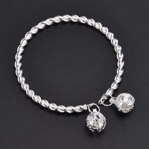 Silver twisted rope bangle with two hollow bell charms on a black background