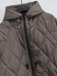 Detail of grey-brown quilted hooded coat featuring diamond stitching and metal zipper closure