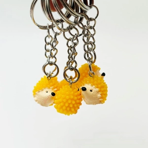 Detailed view of three mini resin hedgehog keychains with silver metal rings and chains