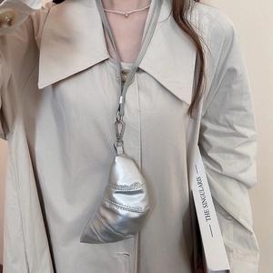 Mini sac collier croissant argenté porté sur un trench beige pour un look Y2K