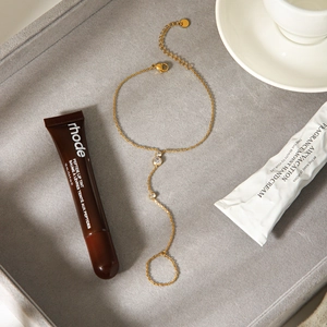 Elegant gold stainless steel finger bracelet with zircon stones on a gray display tray