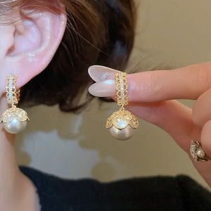 Detailed close-up of retro gold-plated earrings with lace zircon and elegant white pearls