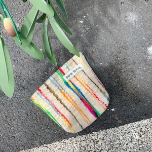 Detail of colorful striped knitted pouch with woven label on asphalt background