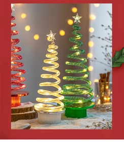 Close-up of red, gold, and green spiral LED Christmas trees on snowy surface decorations