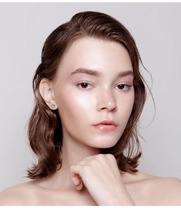 Close-up of golden stud earring with a light blue gemstone on model's ear