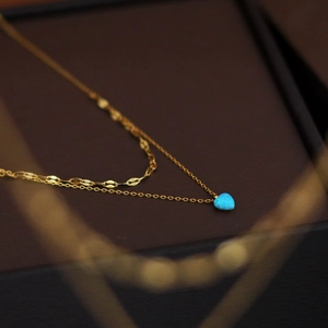 Gold double-layered necklace featuring a heart-shaped blue synthetic opal pendant on black box