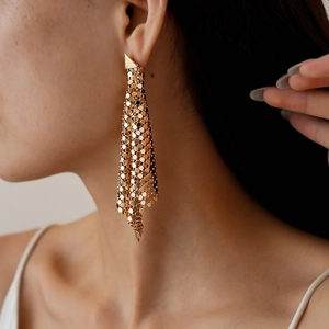 Detail of gold geometric mesh earrings featuring small round sequins in a triangular tassel design