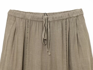 Dettaglio dei pantaloni in lino con coulisse in vita e rifiniture di cucitura traforata