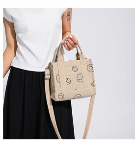 Dettaglio della borsa in velluto beige con stampe smiley e manici rinforzati