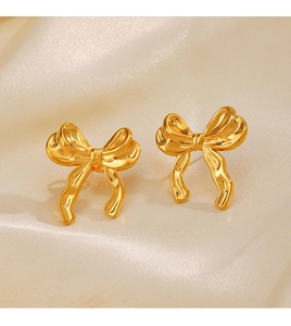 Détail de boucles d'oreilles nœud plaquées or 18K sur fond de soie beige élégant