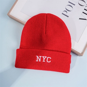 Close-up of white NYC embroidery on red ribbed knit beanie hat with premium stitching