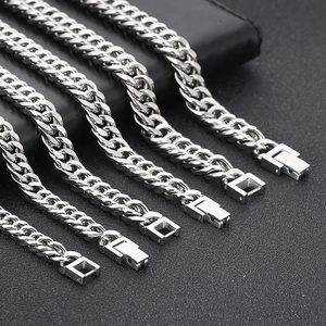 Macro shot of various widths of silver curb chains arranged on a textured black surface