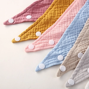 Détail de bavoirs en mousseline de coton pour bébé avec boutons-pression réglables