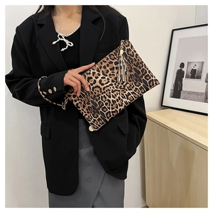 Close-up of leopard print envelope clutch with fringe tassel shown on black suit