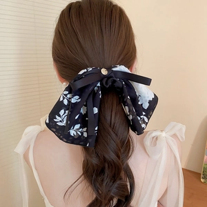 Detail of elegant black and white floral bow hair clip with black ribbons on a model