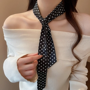 Close-up of black silk-like scarf with white polka dots worn with a beige sweater