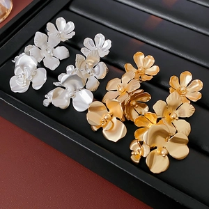 Détails de boucles d'oreilles fleurs en argent et or sur un plateau à bijoux noir