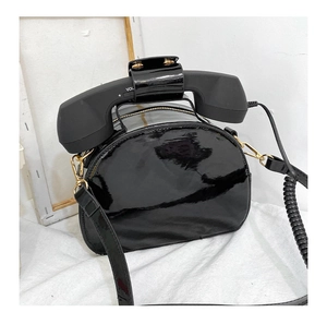 Macro shot of creative telephone handle strap with volume dial on black patent leather bag