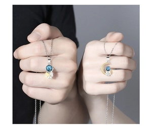Close-up of astronaut couple necklaces with silver pendants and gold crescent moon details