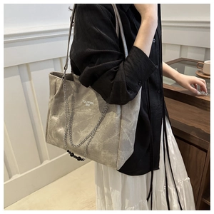 Detailed side view of grey large capacity tote bag with silver chain on model