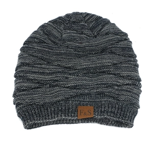Detailed close-up of a black and white knit beanie with a brown F&S leather patch