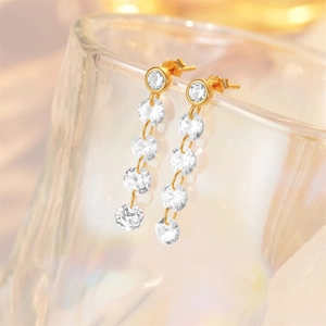 Macro detail of gold S925 silver long drop earrings with clear gemstones on glass