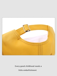 Detail view of the adjustable silver metal buckle on a bright yellow kids baseball cap