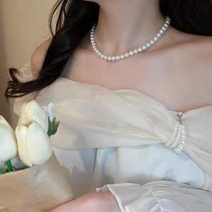 Elegant pearl necklace and matching multi-layer brooch worn by a female model