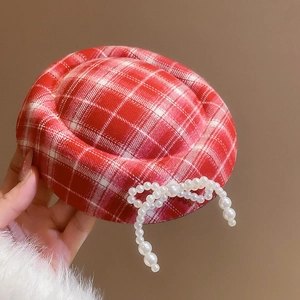 Detailed view of red plaid beret featuring a delicate pearl bow and thick woolen texture