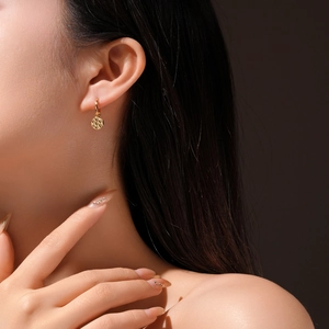 Close-up of elegant gold checkered hoop earrings worn by a model in soft lighting