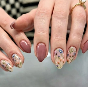 Dettaglio di unghie a mandorla con motivi floreali dipinti a mano e finitura rosa polvere