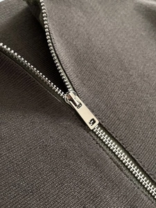 Detailed macro view of high-quality silver metal zipper on ribbed knit fabric texture