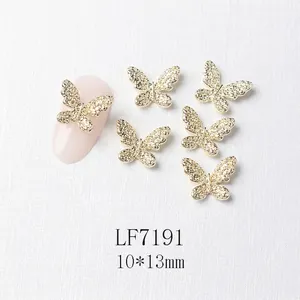 Macro view of 3D gold butterfly nail charm with zircons on a pink manicure display