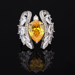 Silver pear-cut yellow gemstone ring with white marquise accents on black background